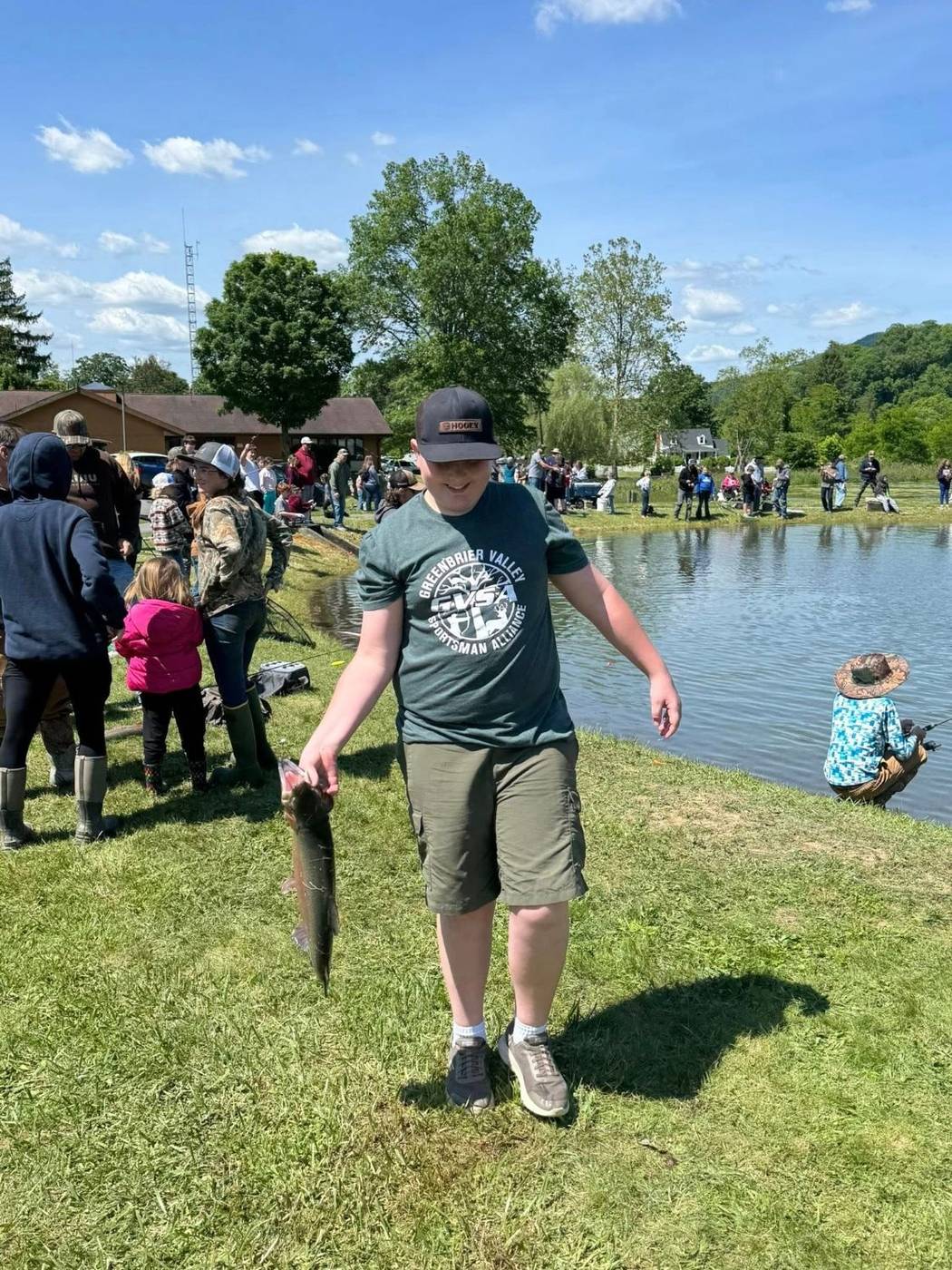 A boy in a GVSA shirt holding up a fish at the Fishing Derby