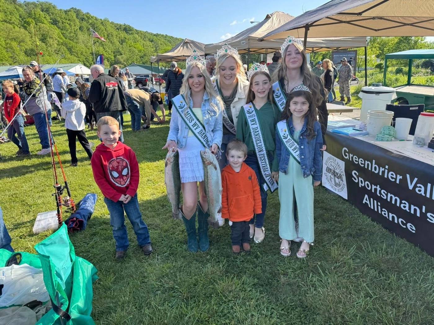 Kids and festival royalty holding trout beside the GVSA table at the Fishing Derby