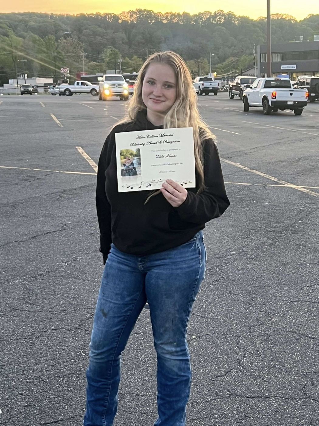 A 2025 scholarship recipient holding her Hattie Rae Callison Memorial Scholarship certificate